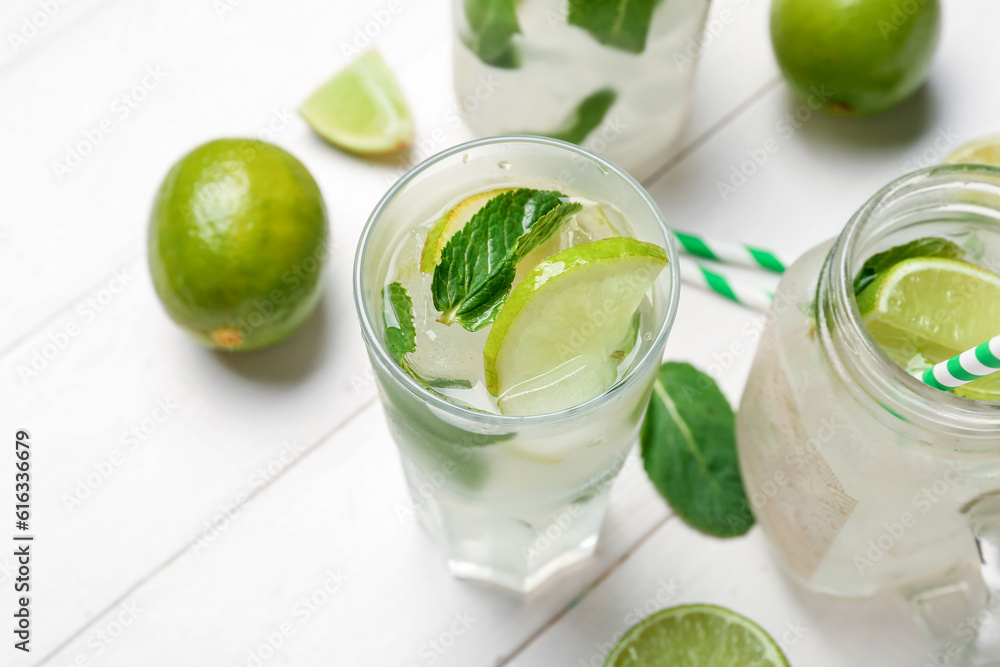 Mason jar and glass of tasty mojito on light wooden background