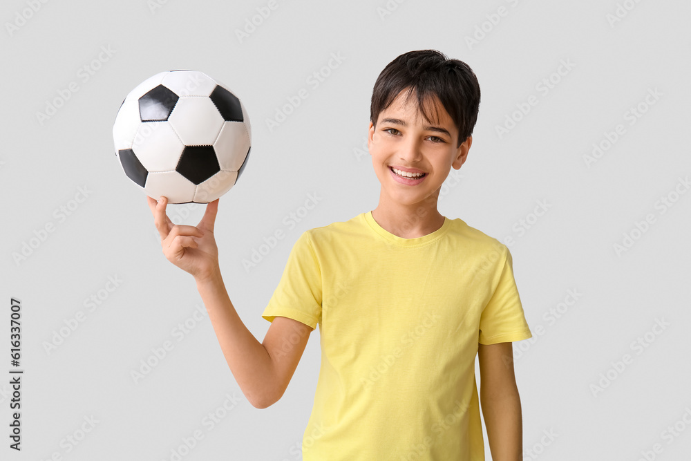 Little boy with soccer ball on grey background