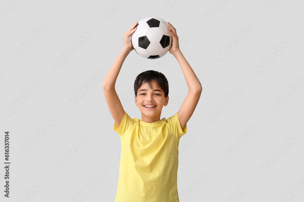 Little boy with soccer ball on grey background