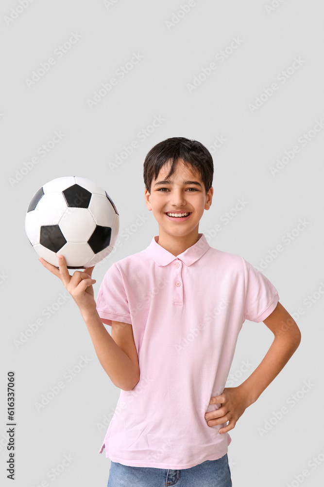 Little boy with soccer ball on grey background