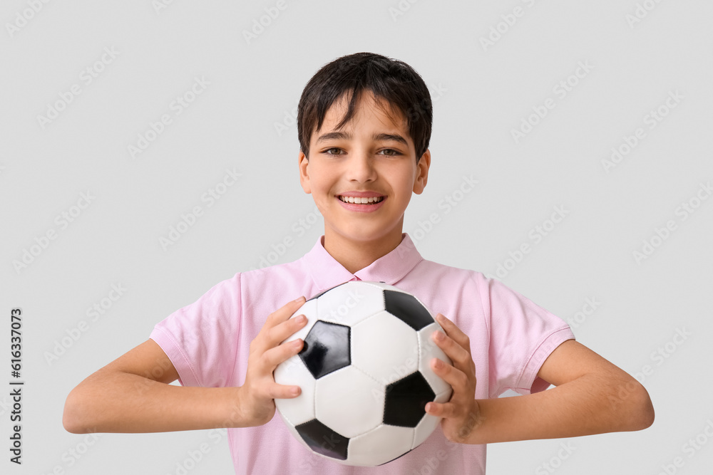 Little boy with soccer ball on grey background