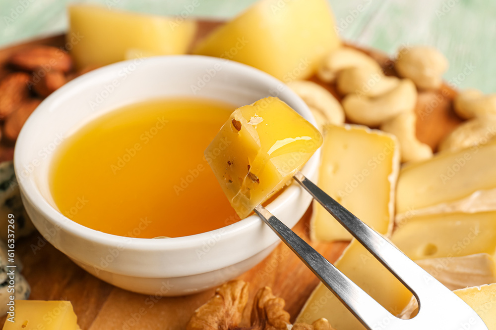 Fork with piece of tasty cheese and honey on table, closeup