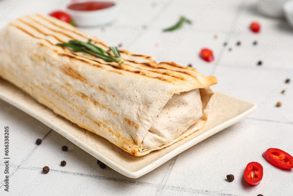 Plate of tasty shawarma with rosemary and chilli on white tile table