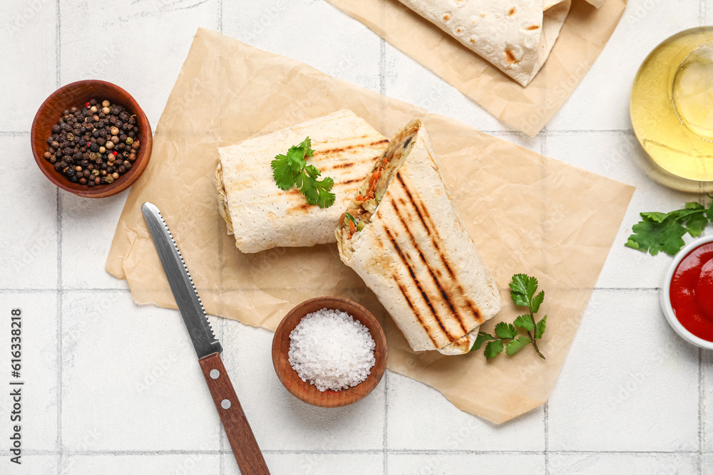 Baking paper with tasty shawarma with parsley on white tile table