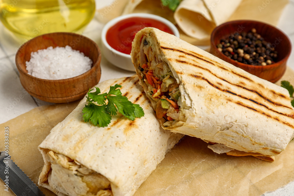 Baking paper with tasty shawarma with parsley on table, closeup