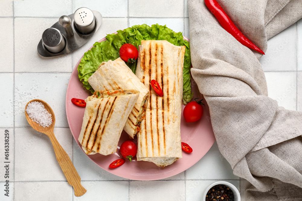 Plate of tasty shawarma with lettuce and tomatoes on white tile table