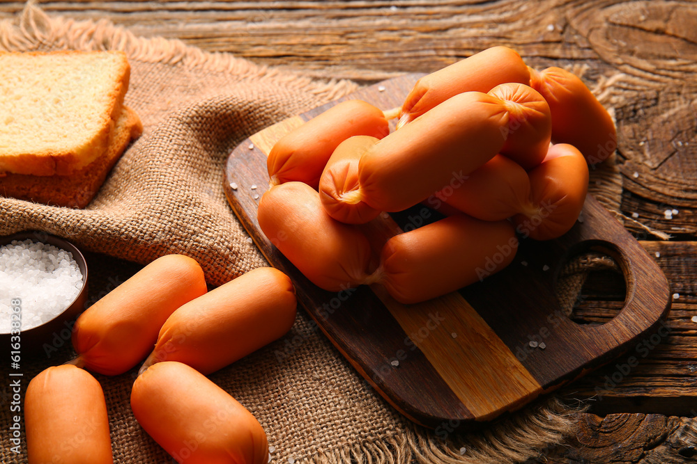 Board of tasty boiled sausages on wooden background