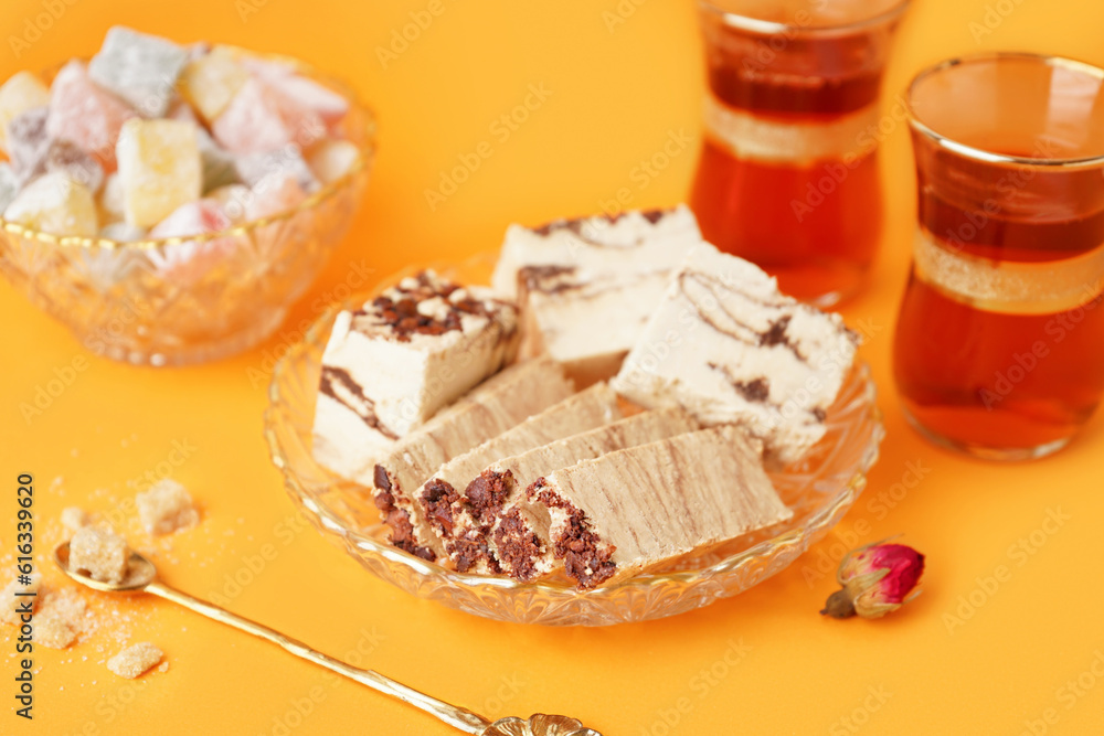 Bowl with pieces of tasty marble halva on orange background