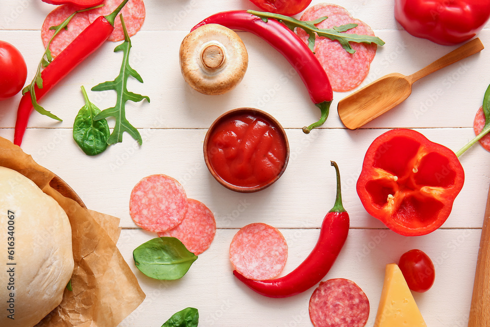 Raw dough and ingredients for preparing pizza on light wooden background