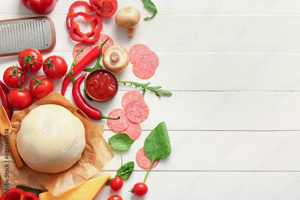 Raw dough and ingredients for preparing pizza on light wooden background