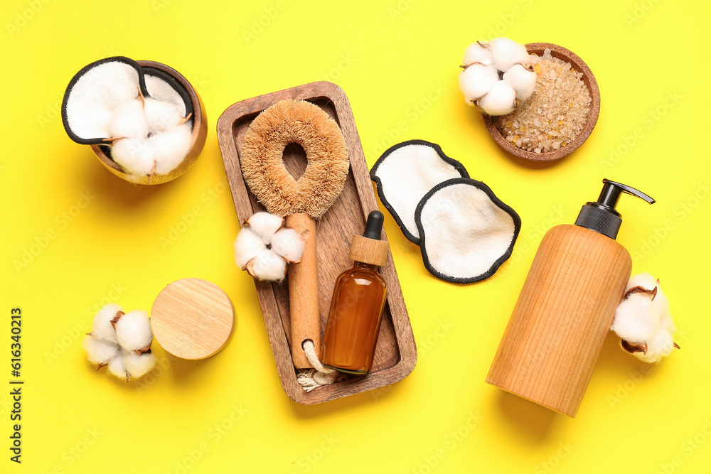 Composition with bath supplies, cosmetics and cotton flowers on yellow background