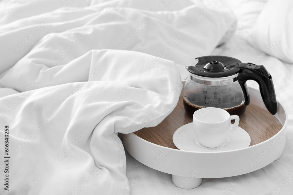 Tray with coffee pot and cup in bed