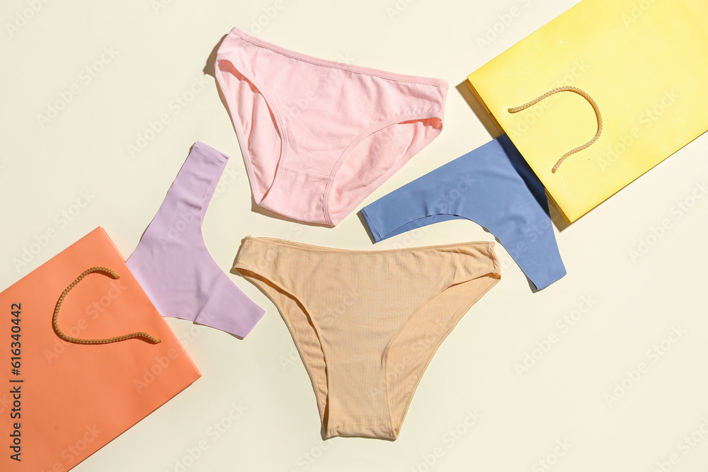 Set of stylish female panties and paper bags on light background