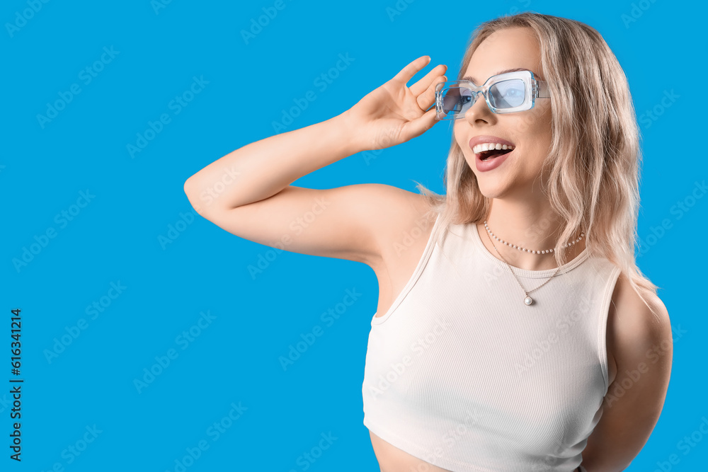 Young woman in stylish sunglasses on blue background