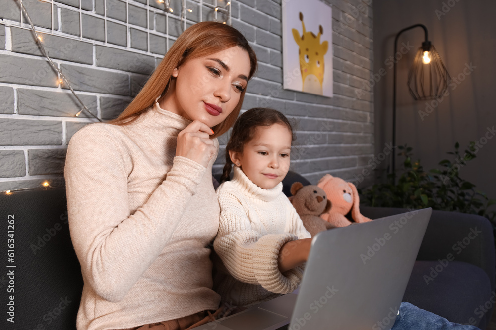 Little girl with her mother doing lessons at home late in evening