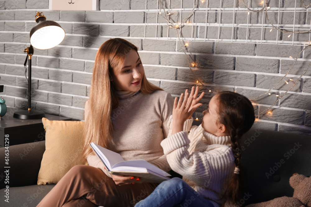 Little girl with her mother doing lessons at home late in evening