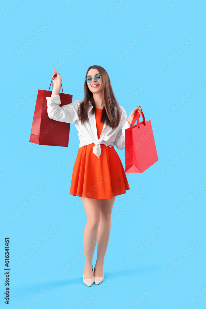 Young woman with shopping bags on blue background