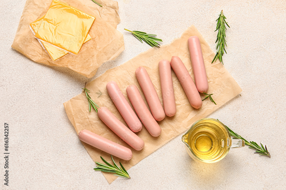 Baking paper with tasty thin sausages and cheese on white background