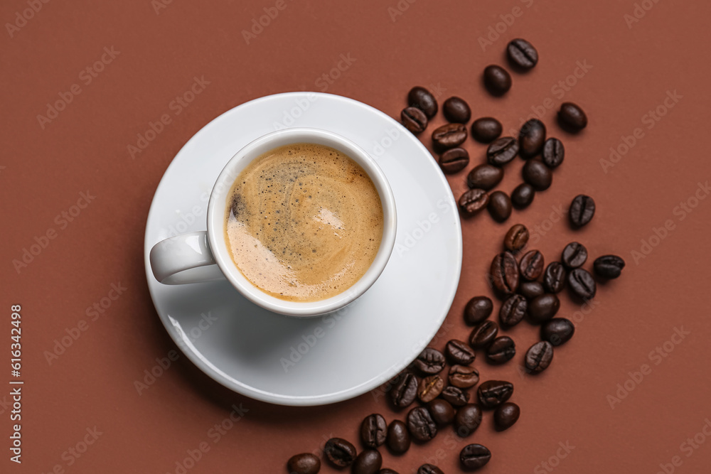 Cup of hot espresso and coffee beans on brown background