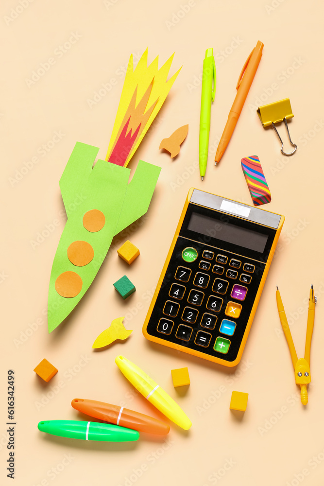 Paper color rockets with calculator, pens and compass on beige background