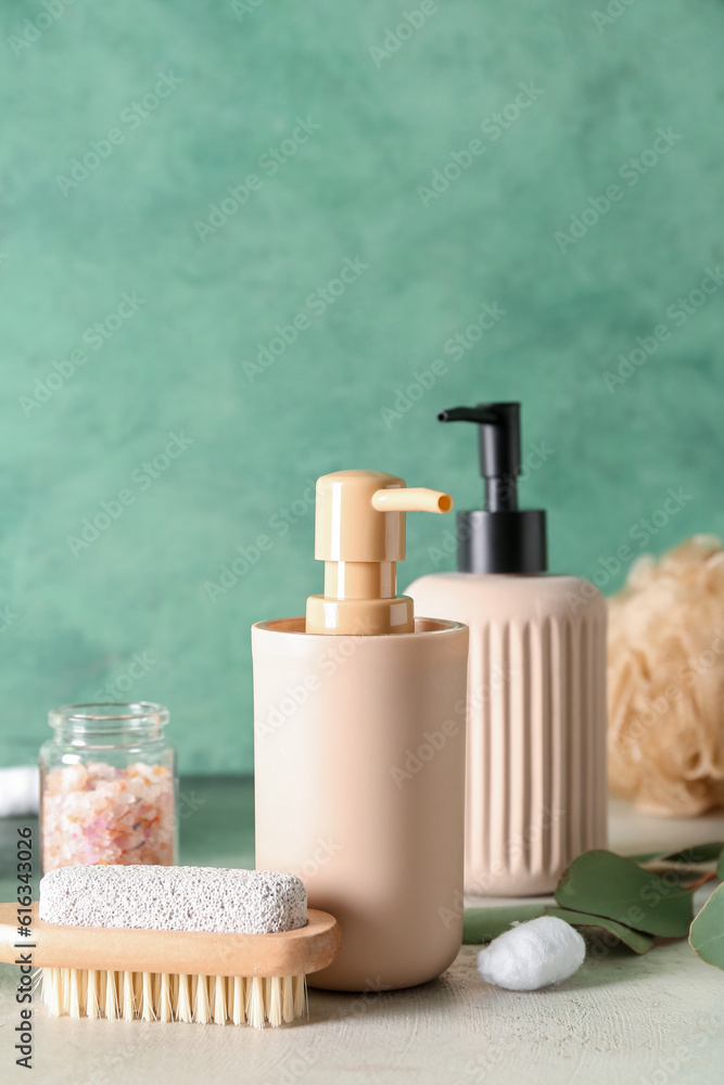 Bottles of cosmetic products, massage brush and sea salt on color background