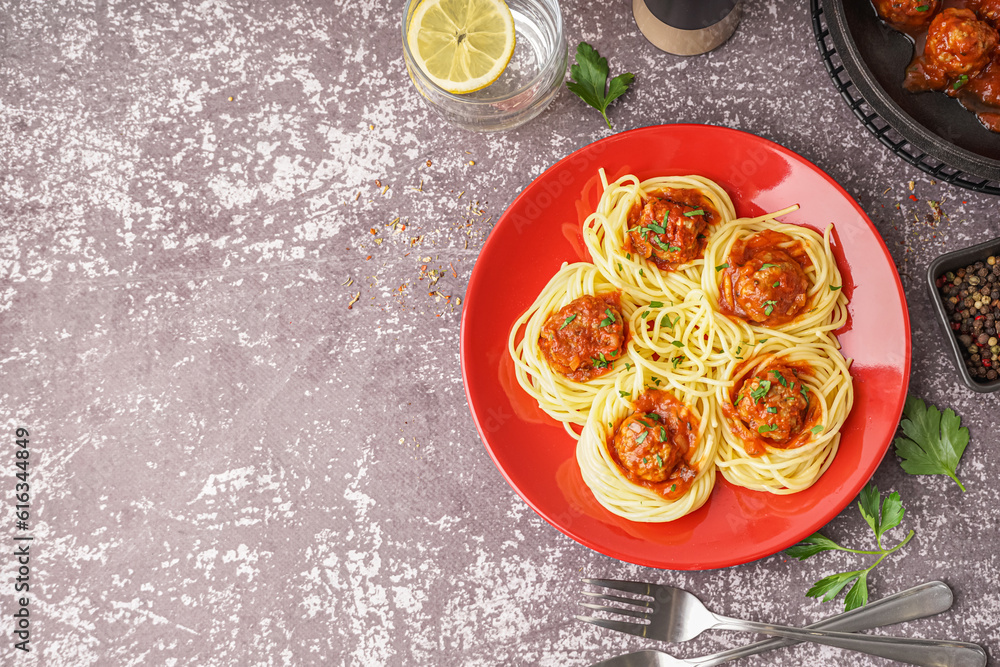 Plate of boiled pasta with tomato sauce and meat balls on grey table