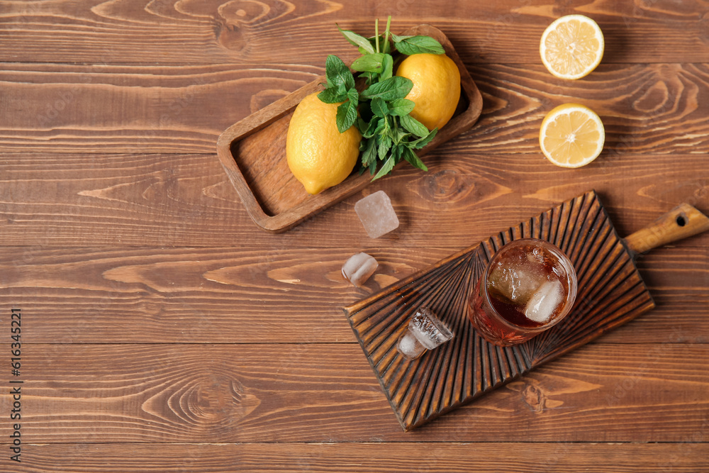 Boards with glass of ice tea and lemon on wooden background