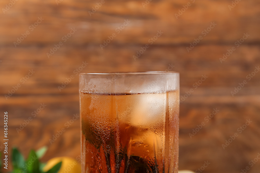 Glass of ice tea with mint on wooden background