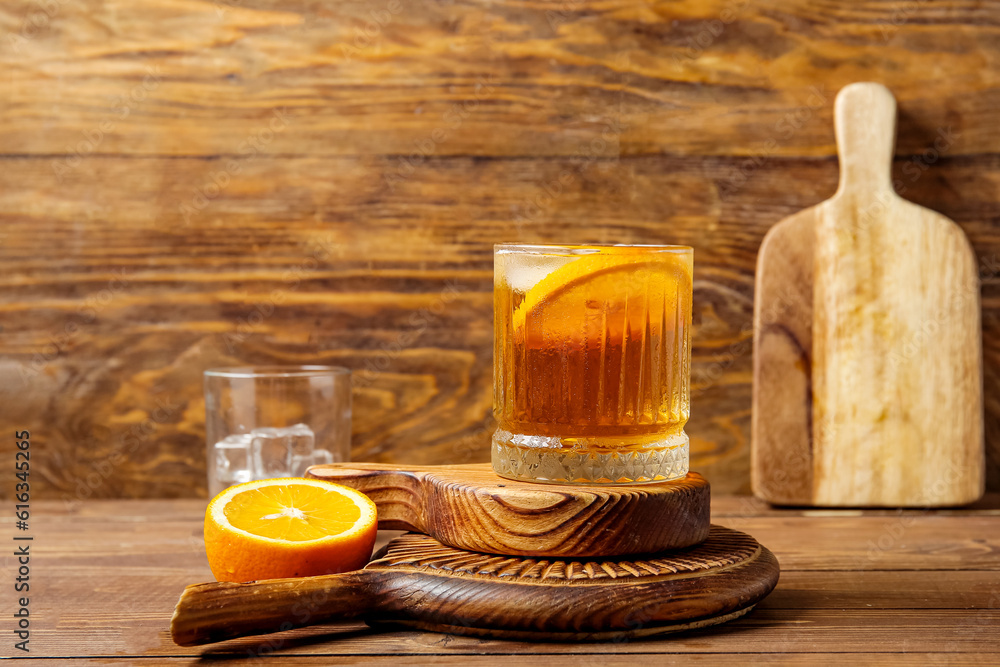 Boards with glass of ice tea and orange on wooden background