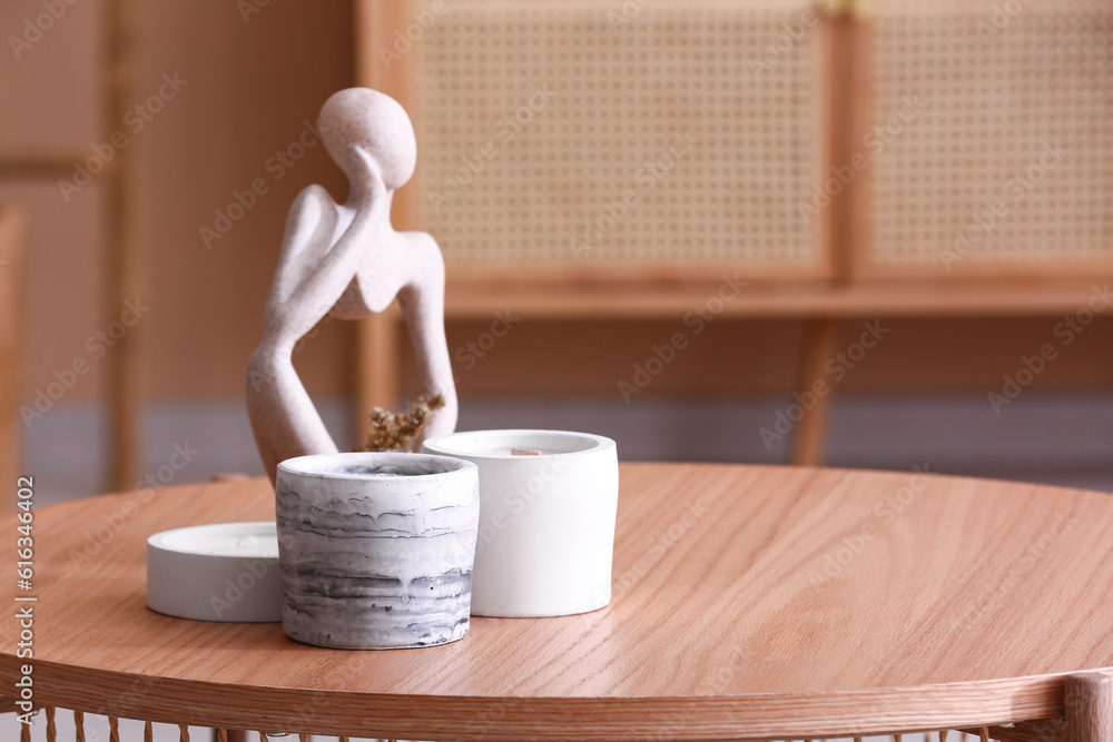 Holders with candles and decor on table in room, closeup