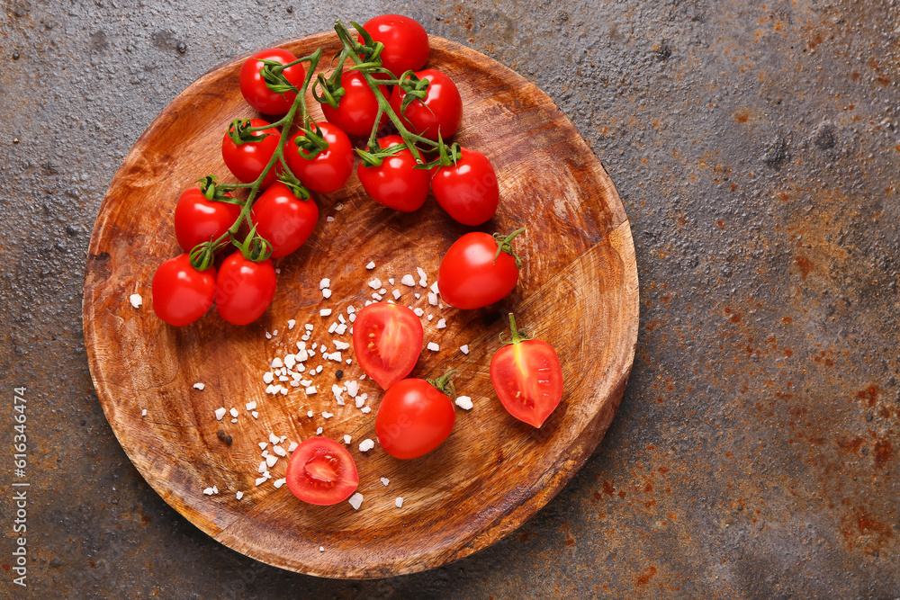 Wooden plate with fresh cherry tomatoes on dark background