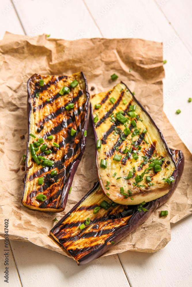 Delicious grilled eggplants on light wooden background