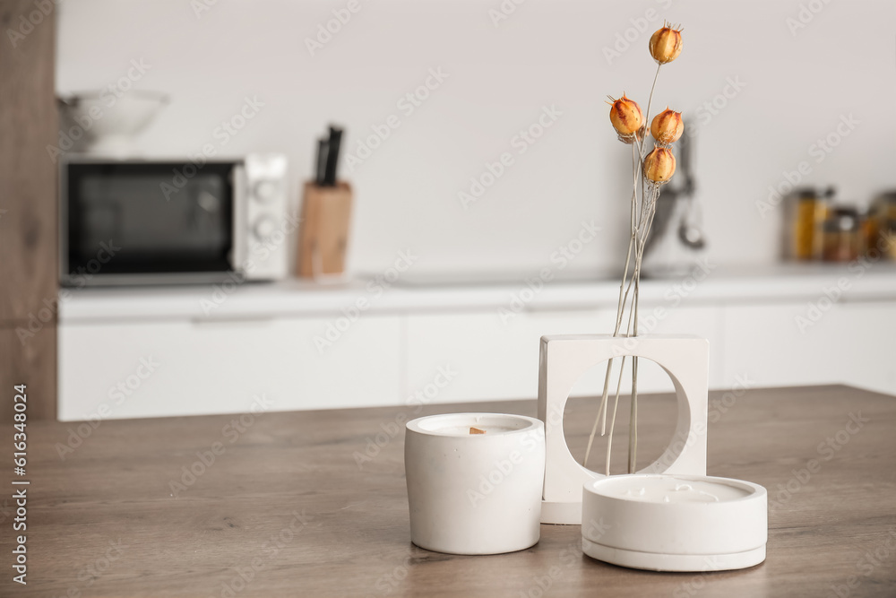 Dried flowers and candles on table in light kitchen, closeup