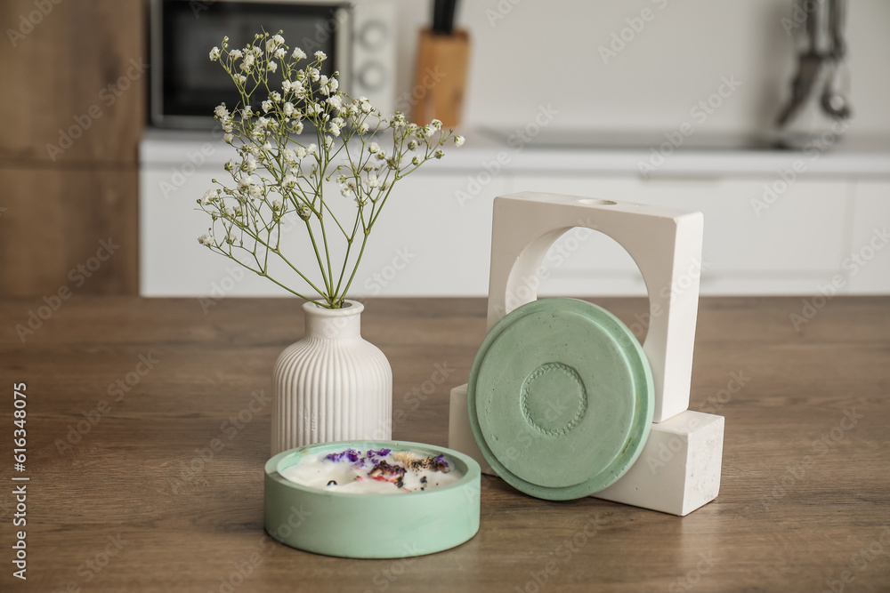 Gypsophila flowers and candle on table in light kitchen, closeup