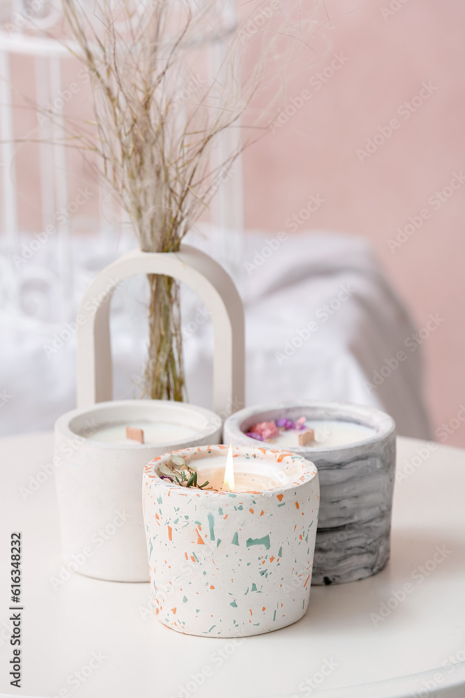 Holders with candles on table in light room, closeup