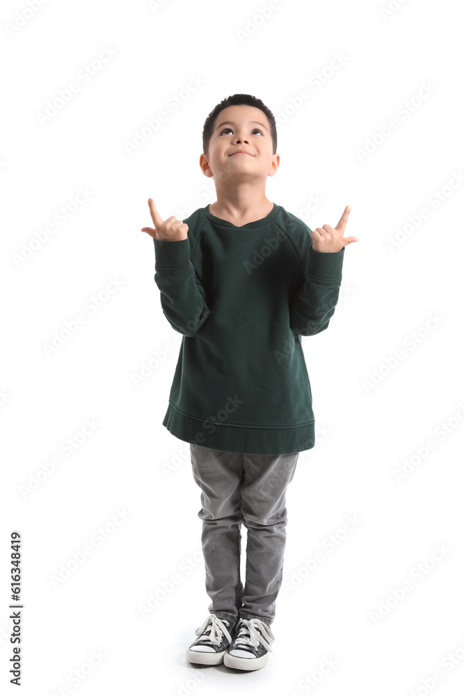 Cute little boy in knitted sweater pointing at something on white background