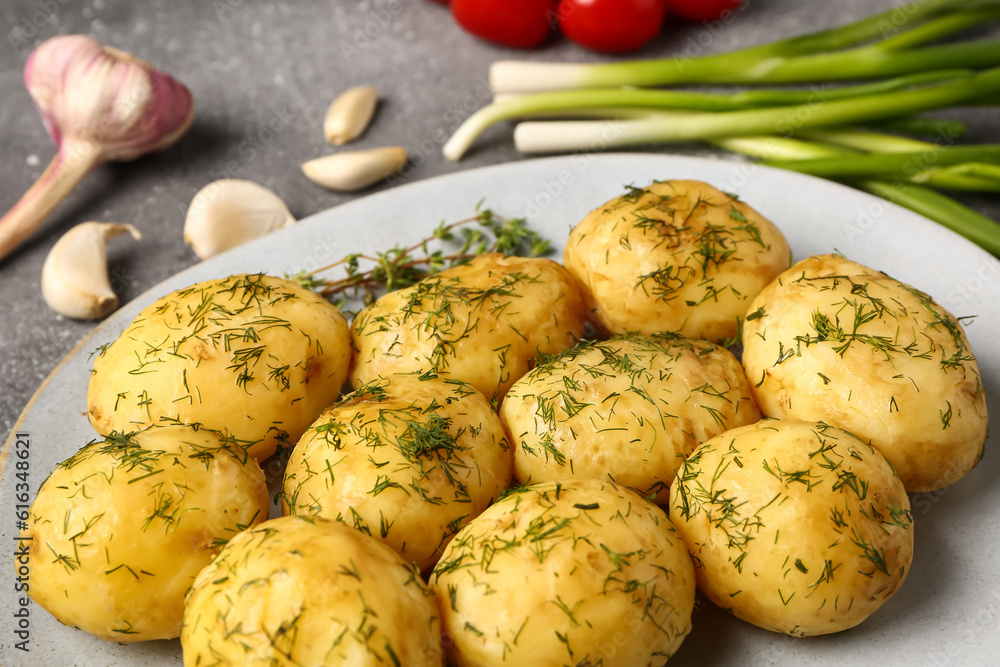 Plate of boiled baby potatoes with dill and garlic on grey background