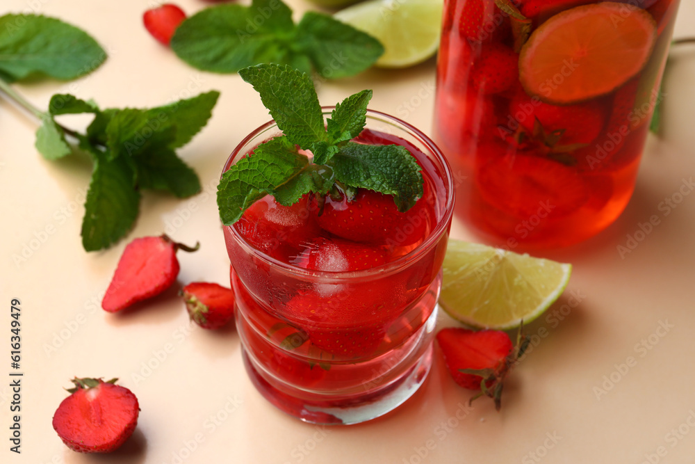 Glass and bottle of infused water with strawberry and lime on beige background