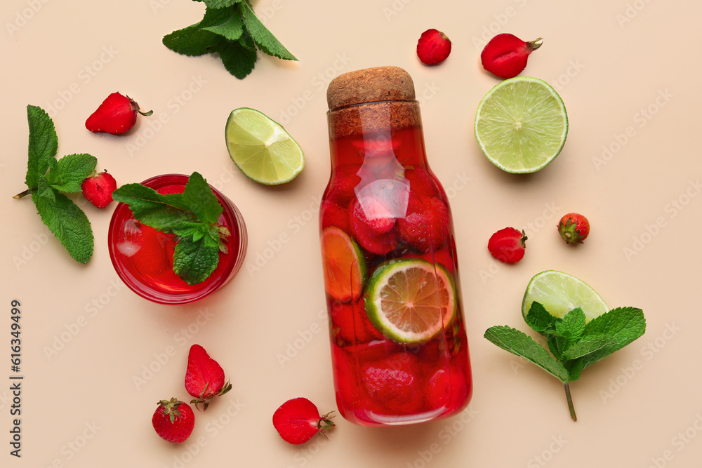 Glass and bottle of infused water with strawberry and lime on beige background