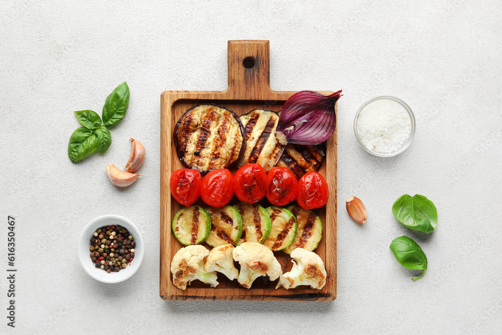 Wooden board with grilled vegetables on white background