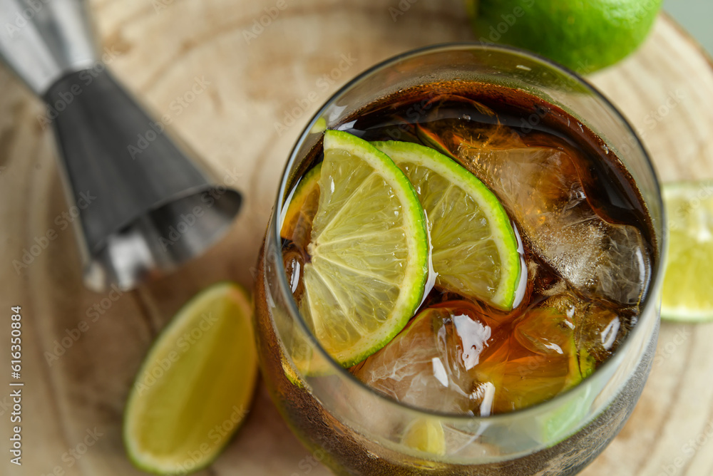 Glass of cold Cuba Libre cocktail on wooden table