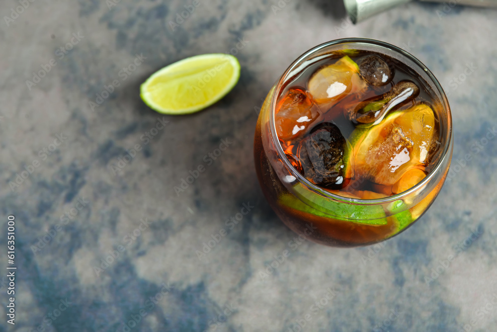 Glass of cold Cuba Libre cocktail on purple background