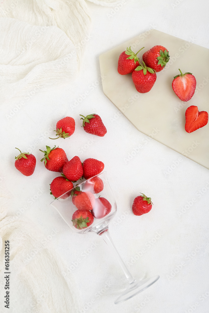 Glass and board with fresh strawberries on white background