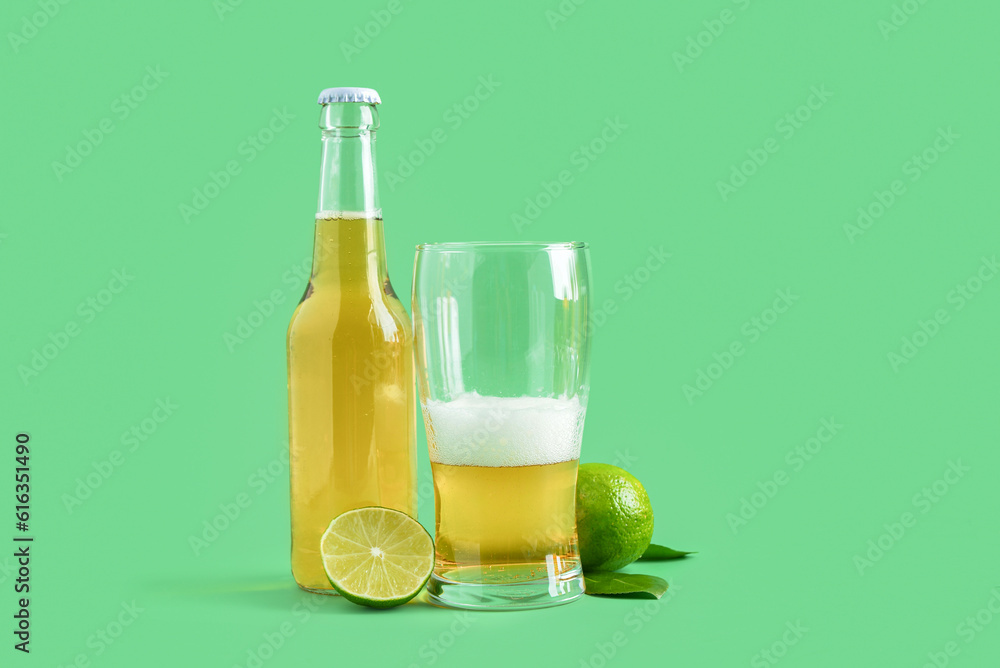 Glass and bottle of cold beer with lime on green background