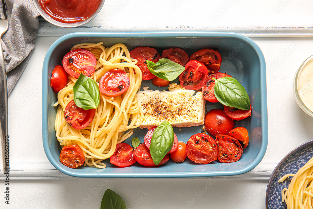 Baking dish of tasty pasta with tomatoes and feta cheese on white wooden background