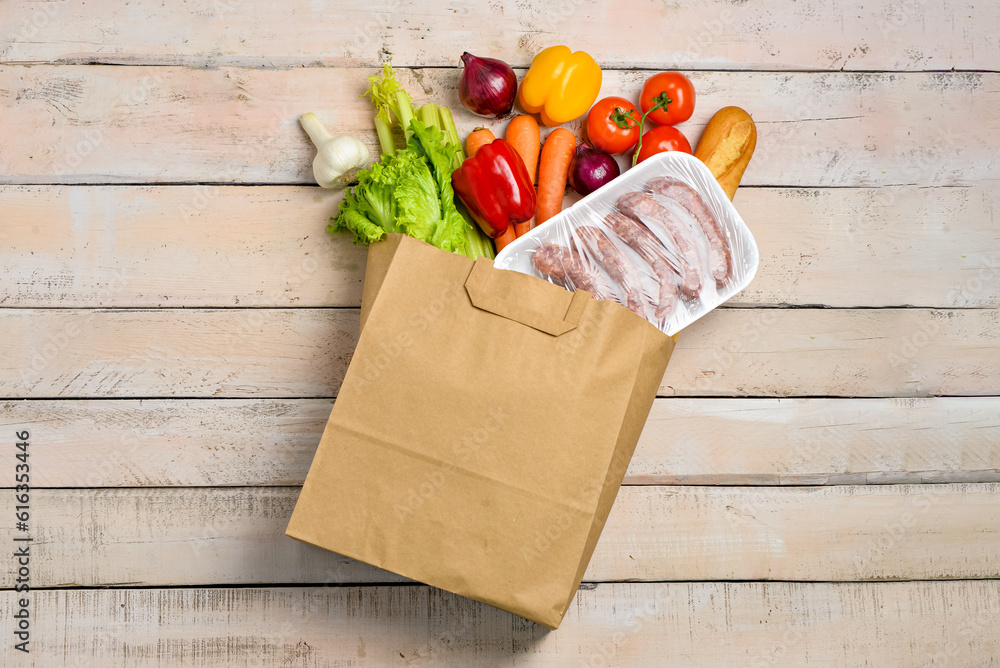 Paper bag with different products on light wooden background