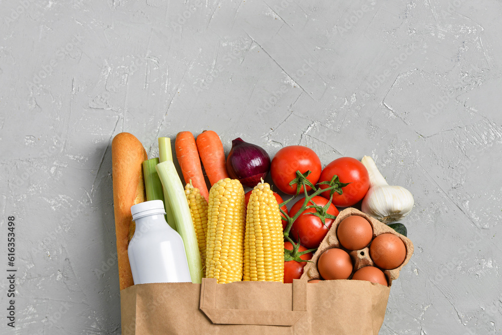 Paper bag with different products on grey background