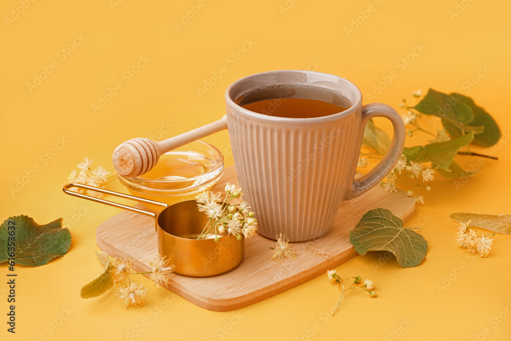 Cup of linden tea and bowl with honey on orange background