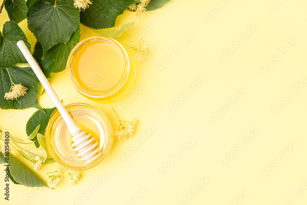 Jar and glass bowl with linden honey on yellow background