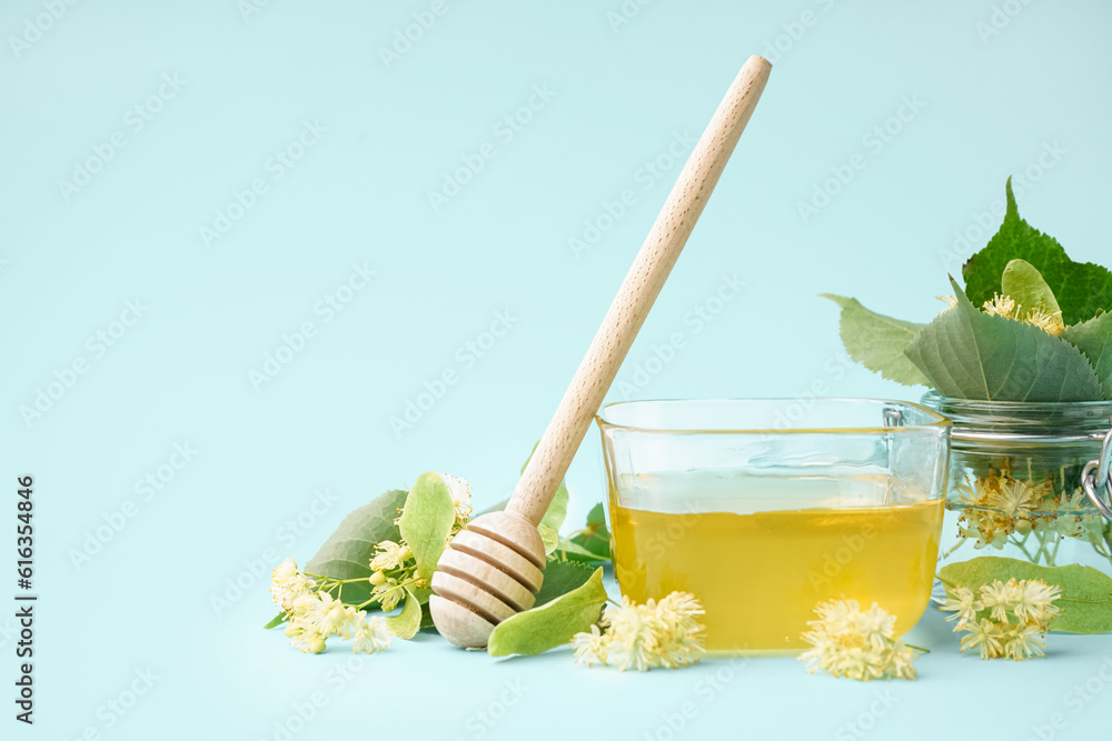 Glass bowl with linden honey and dipper on blue background